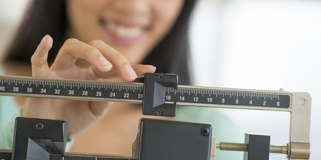 a woman weighing herself with a doctor's scale