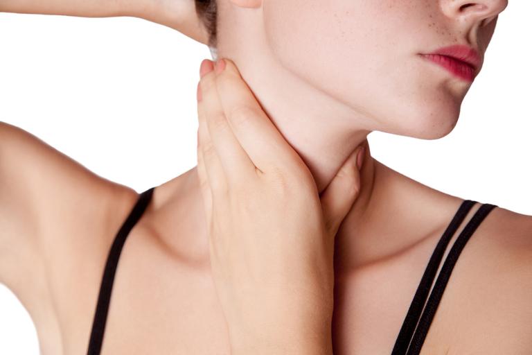 Closeup view of a young woman with pain on neck or thyroid gland.